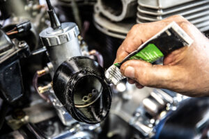 Applying a bead of RTV silicone to the air box adapter boots for Murray's Triumph Speedmaster Carburetor Kit. 