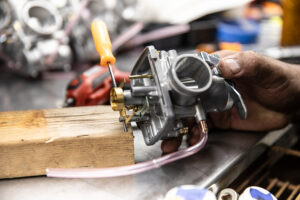 Gently removing the Mikuni carburetor body and float pin from the block. 