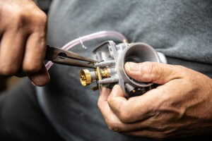 Pressing in a Mikuni VM series carburetor float tang pin with needle nose pliers. 