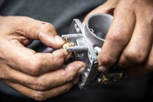 Threading in the Mikuni float needle seat, buffer plate, and gaskets by hand. 